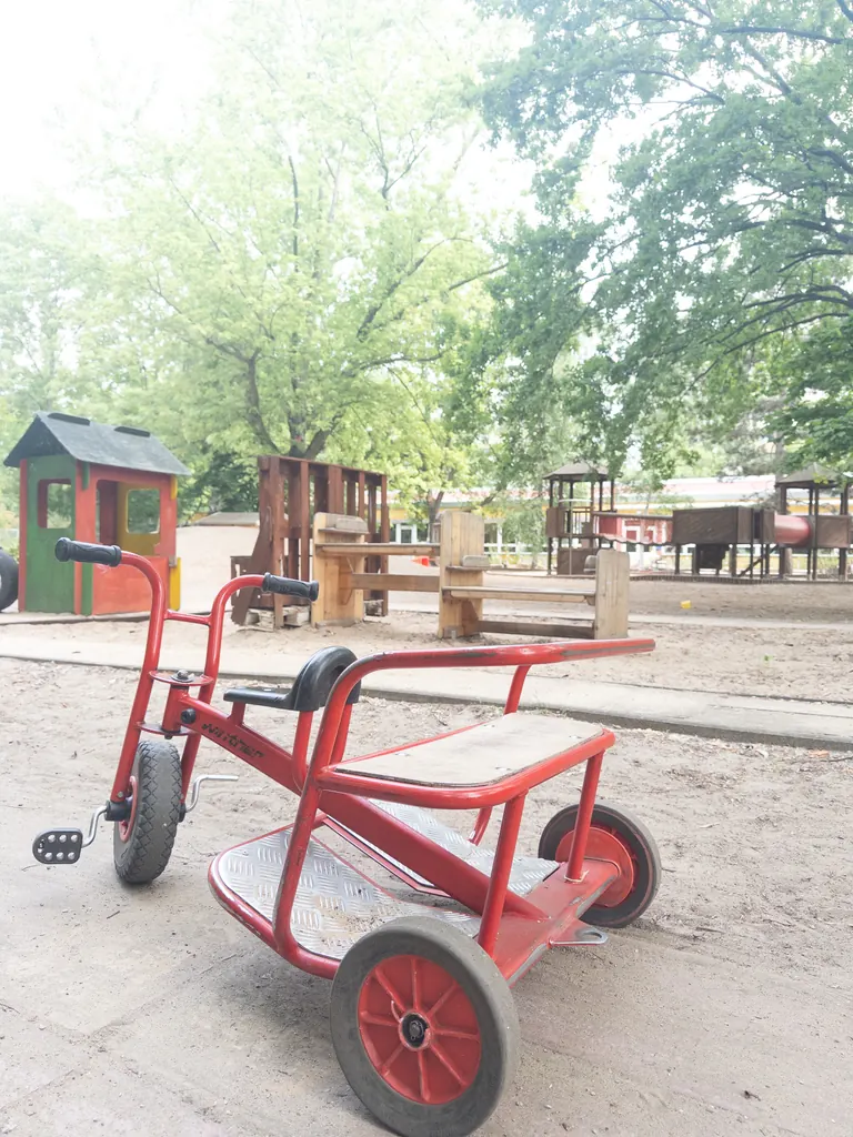 Dreirad und Spielhaus auf dem Kita-Spielplatz